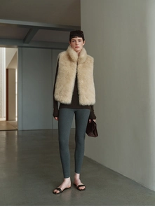 Detail view of a plush beige faux fur vest styled with a dark brown long-sleeve knit top