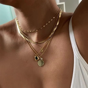Layered gold titanium necklace set with S pendant and black gemstone on female neck