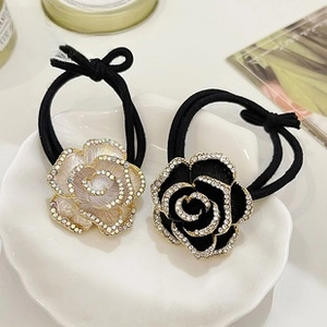 Detail of elegant camellia hair ties with sparkling rhinestones in white and black