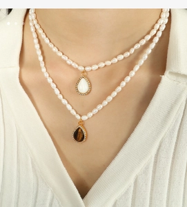 Dettaglio della collana di perle a doppio strato con ciondoli a goccia e strass dorati