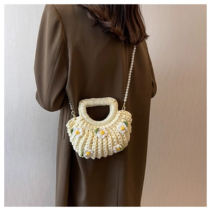 Detailed back view of a beige woven shell bag with 3D daisies and pearl strap detail