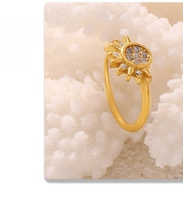 Macro shot of gold sun ring with tiny zircon stones on white coral stone backdrop