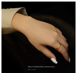 Close-up of double layer gold ring with delicate chain on model hand and dark background