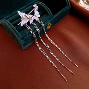 Détail d'un clip d'oreille papillon argenté avec de longues franges irisées sur velours