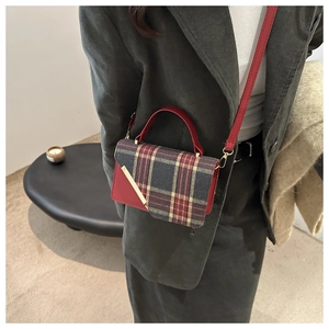 Close-up of a retro plaid crossbody bag with red trim and gold hardware on a model