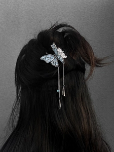 Macro shot of silver butterfly hair clip with blue zircon stones and long tassel fringe