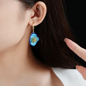 Close-up of vintage irregular floral earring with blue enamel and gold flower details