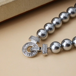 Macro shot of grey pearl necklace with a silver geometric clasp and white zircon stones