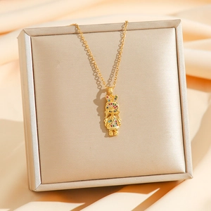 Goldene Kette mit buntem Zirkonia-Mädchen-Anhänger auf einer champagnerfarbenen Schmuckbox