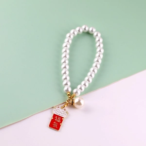 Macro detail of white pearl phone chain with a red Maneki Neko lucky cat charm