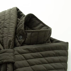 Detailed view of quilted stitching and matte button on dark green nylon jacket