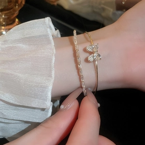 Close-up of elegant gold zircon bow bangle and shimmering rhinestone bracelet set