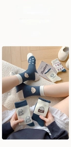 Détail de chaussettes mi-hautes en coton bleu avec motif chien et bordure ondulée