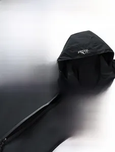Detail view of black outdoor hooded jacket featuring windproof cap and zip pockets