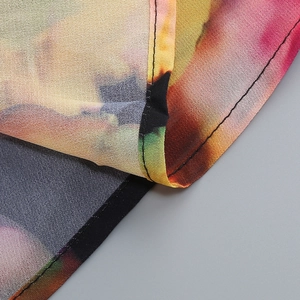 Macro detail of the fine stitching and colorful floral print on lightweight chiffon fabric