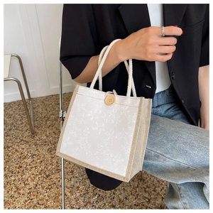 Detail of canvas tote bag with floral embroidery and a wooden button closure