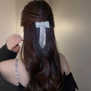 Gros plan d'une pince à cheveux nœud en strass avec chaînes à franges sur cheveux sombres