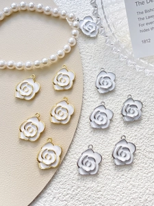 Detail of white enamel camellia pendants with gold and silver bases for DIY jewelry