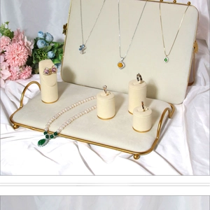 Macro view of velvet jewelry display stands with gold metal bases on white silk fabric