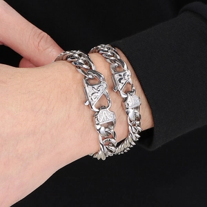 Close-up of polished silver double-weave Cuban chain bracelets on a model's wrist