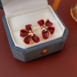 Macro detail of vintage red enamel flower earrings with zircons in a jewelry box