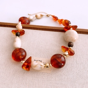 Detailed shot of amber and marble acrylic beads on a stylish Maillard style necklace