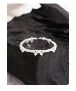 Macro shot of S925 sterling silver bow ring with embossed texture on dark charcoal
