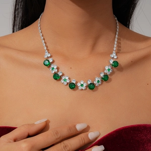 Close-up of luxury flower necklace with green stones on elegant red velvet background