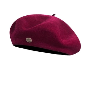 Elegant deep wine red wool beret for women with a vintage metal emblem on white background
