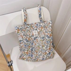 Dettaglio della borsa tote in tela floreale con etichetta tessuta su una sedia minimalista