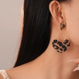Gros plan détaillé d'une boucle d'oreille en résine léopard en forme de cœur sur un mannequin