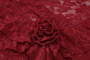 Detailed macro view of dark red lace fabric and handmade rose flower on the dress