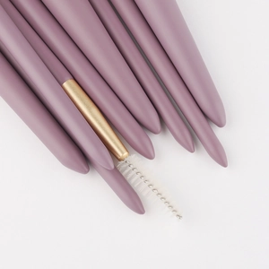 Set de 9 pinceaux de maquillage violets avec manches mats et viroles dorées sur fond blanc