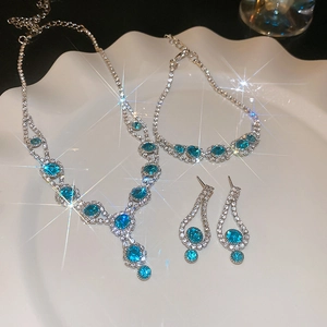 Close-up of a silver jewelry set featuring blue crystal flowers on a white plate