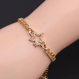 Detail of gold star charm bracelet featuring micro-pave cubic zirconia on a Cuban link