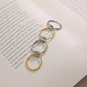 Stackable gold and silver stainless steel rings with twisted and beaded texture on book