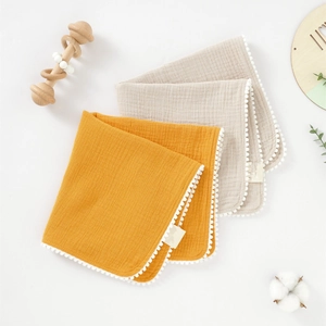 Détail de lingettes bébé en gaze de coton double couche avec bordure décorative à pompons
