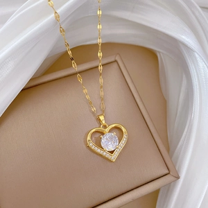 Close-up of heart-shaped gold necklace with zircon stones on silk fabric