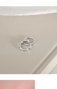 Macro detail of silver bamboo-style hoop earrings featuring minimalist textured nodes