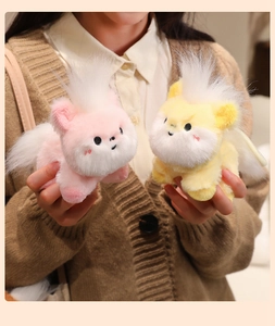 Close-up of cute pink and yellow plush horse keychains held in hand for bag decoration