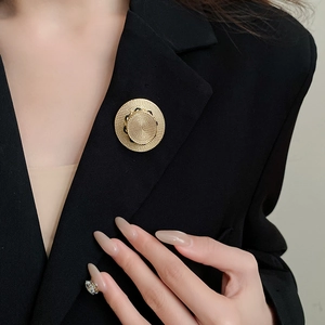 Makro-Detail der goldenen runden Brosche mit Webmuster auf schwarzem Blazer-Revers
