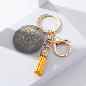 Detailed shot of wooden MAMA keychain with yellow leather tassel and gold lobster clasp