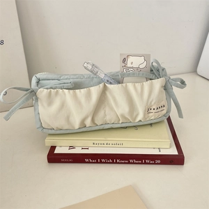 Detail of blue quilted pencil case with ribbon bows and large storage pockets