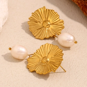 Dettaglio di orecchini placcati oro 18K con perle barocche su sfondo in pietra