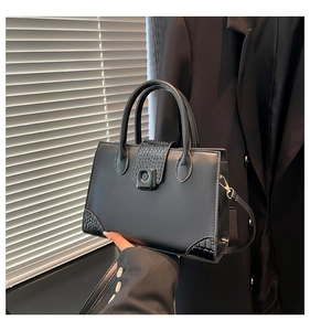 Close-up of black crocodile embossed leather panels and gold hardware on fashion handbag
