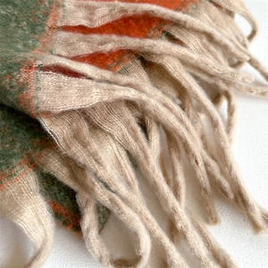 Macro detail of soft cashmere-like tassels and colorful plaid texture on long winter scarf