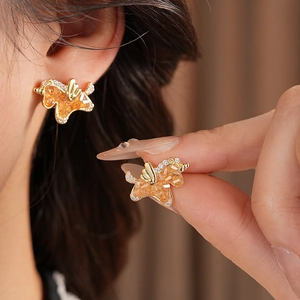 Macro detail of Pegasus stud earrings with amber zircon and small sparkling crystals