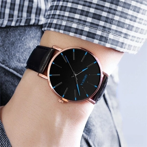 Close-up of minimalist black dial watch with blue markers and rose gold case on wrist