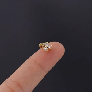 Close-up of a gold flower cartilage stud with three zircons held on a fingertip