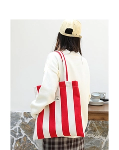 Detail of red and white striped canvas tote bag with SEASON 12 text worn by a model